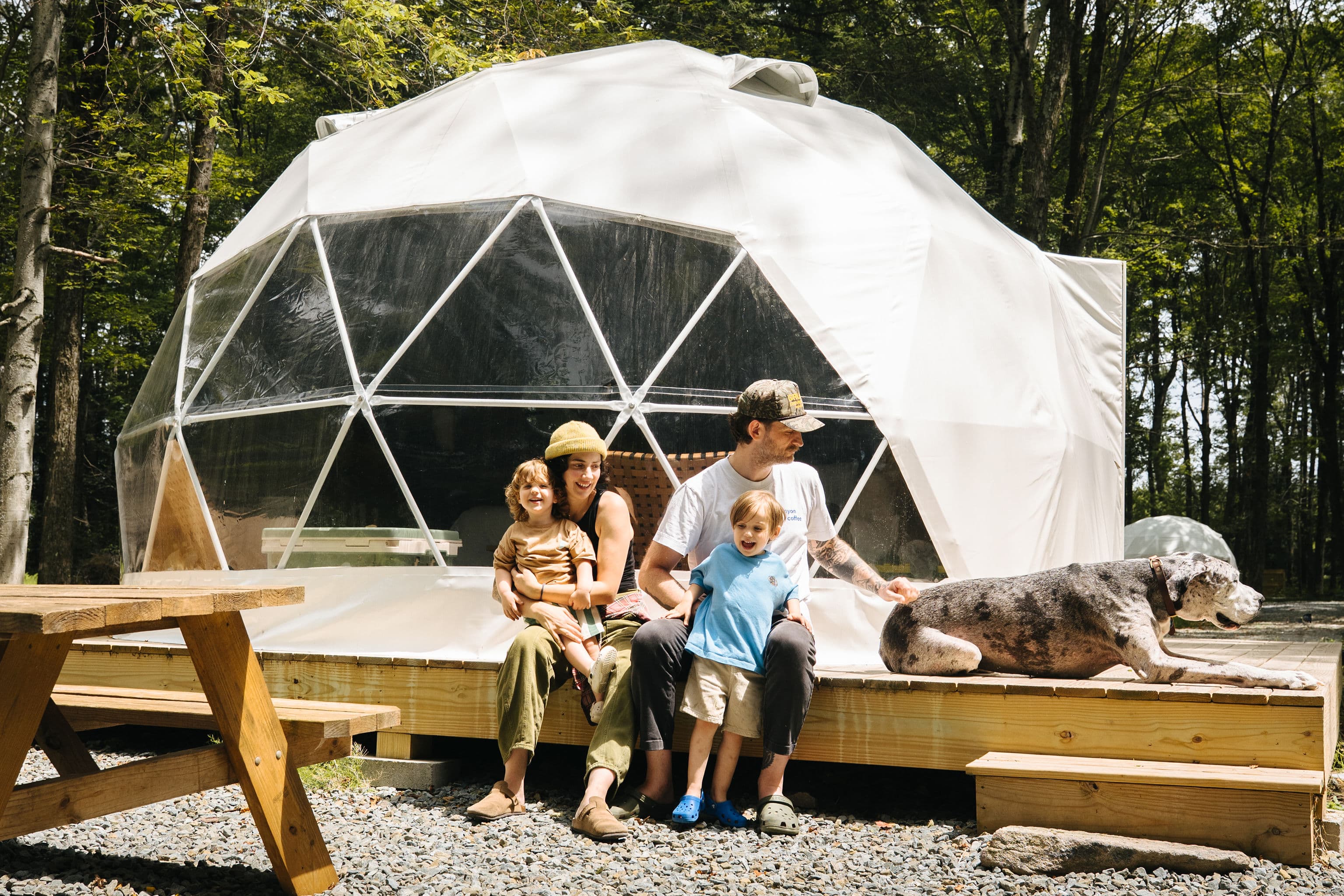 A family with their dog sitting on the deck of a Ferncrest dome